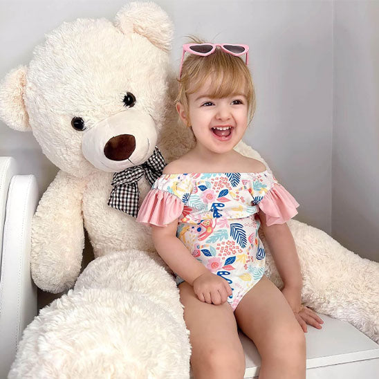 Ours en peluche blanc assis avec petite fille rire